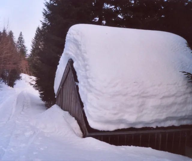 Holzhütte mit meterhohem Schnee auf dem Dach